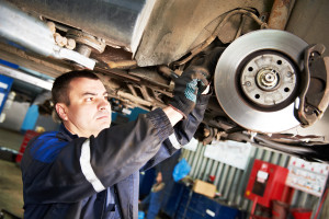 automobile mechanic inspecting car wheel brake disc and shoes of