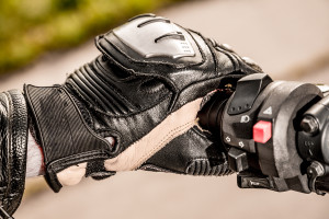 Human hand in a Motorcycle Racing Gloves holds a motorcycle thro