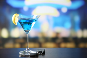 Glass of alcoholic drink and car key, on wooden table, on light