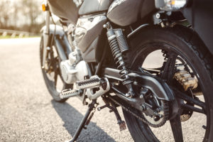 Close up shock absorber, chain and disk brake of black shiny motorcycle